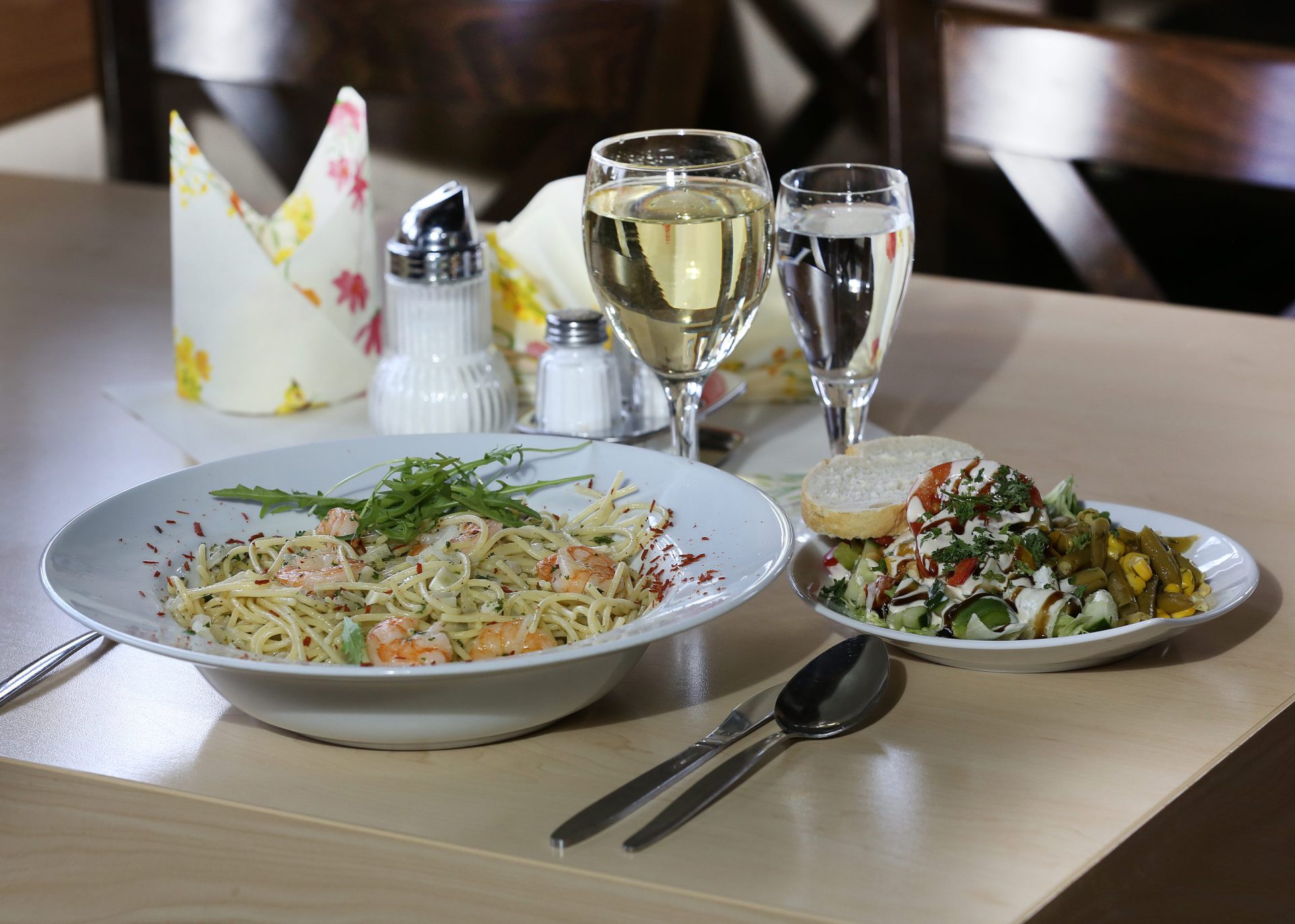 Teller mit Salat und Beilagen, dazu ein Glas Wein